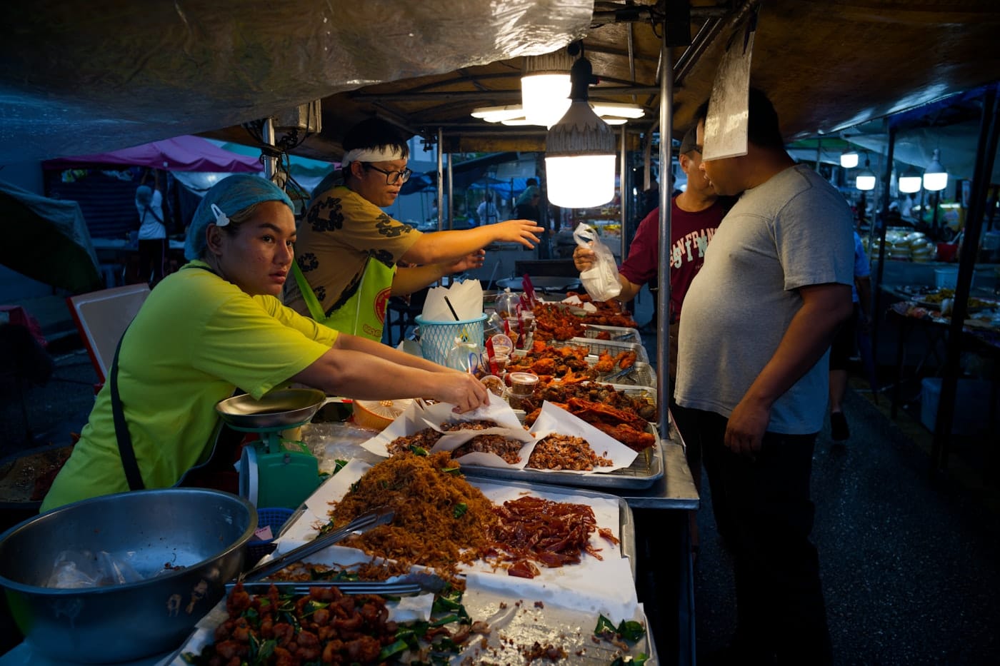 Vendors serve food at a busy night market stall
