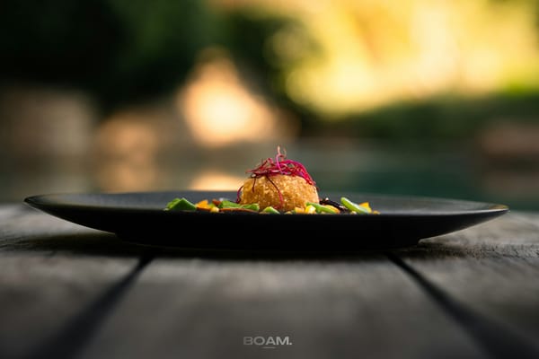 A black plate topped with food on top of a wooden table
